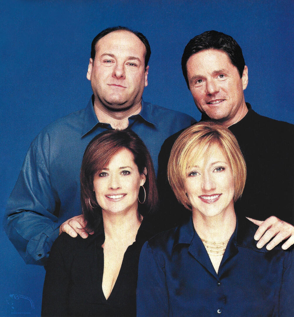 Forbes Table of Contents extra of The Sopranos cast members James Gandolfini, Lorraine Bracco, and Edie Falco posing with television producer Brad Grey against a solid blue background.