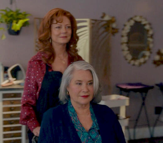 6 Susan Sarandon standing behind a seated Lorraine Bracco in a hairdressing scene from Nonnas movie.