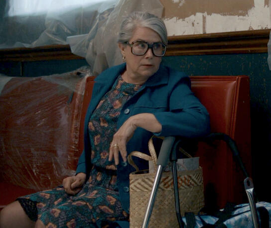 5 Lorraine Bracco in a blue jacket sitting next to a walker in a scene from the comedy Nonnas.