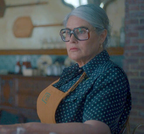 10 Lorraine Bracco wearing giant glasses and a polka dot shirt in a scene from the movie Nonnas.