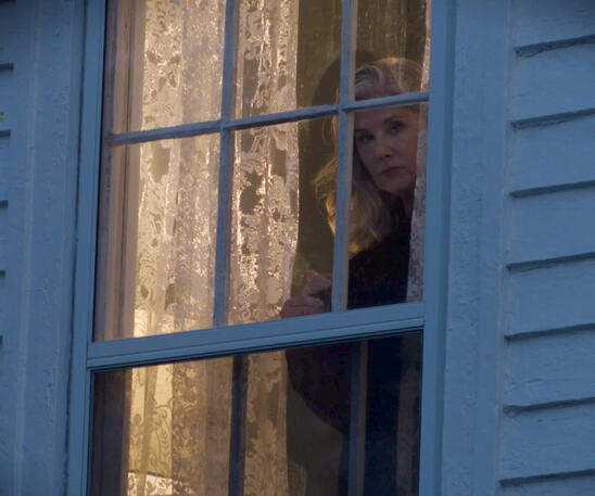 5 Lorraine Bracco peeking out from behind a framed window in Monster Summer.