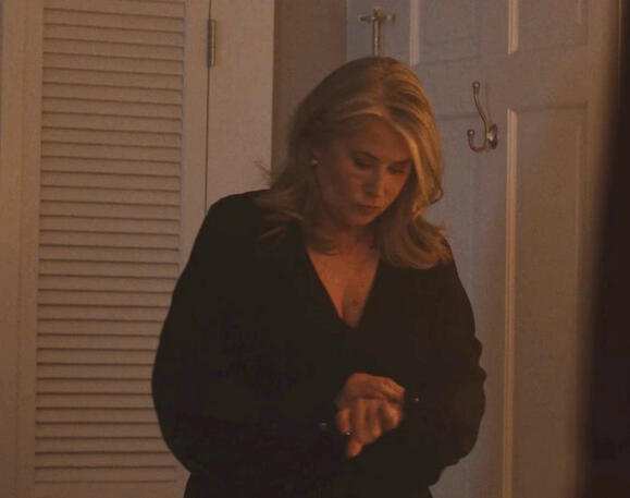 8 Lorraine Bracco checking her wrist watch indoors in a dark outfit in Monster Summer.
