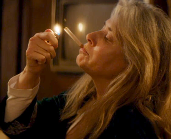 9 Lorraine Bracco lighting a cigarette in a dark room, scene from Jacir movie.