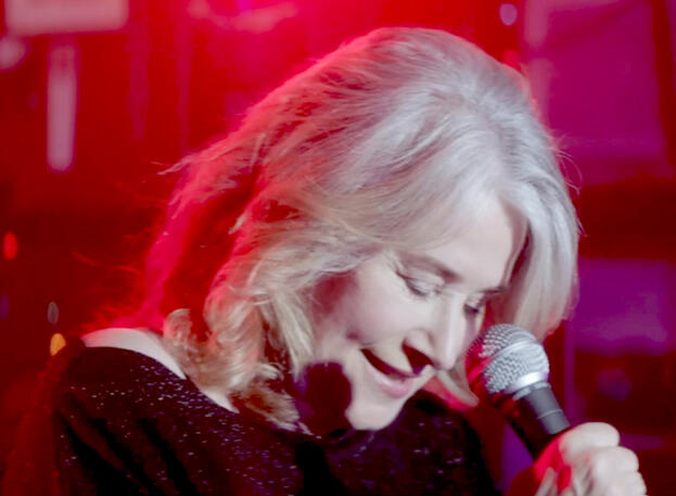 10 Lorraine Bracco singing into a microphone under red lights in Jacir movie.