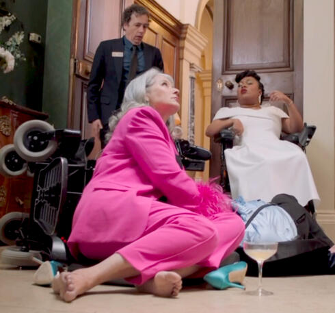 5 Lorraine Bracco sitting on the floor in a bright pink suit in the series Jerk.