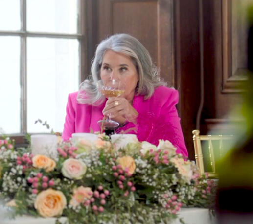 7 Lorraine Bracco sipping from a glass behind floral arrangements at her son's wedding in Jerk.