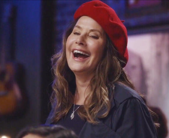 6 Lorraine Bracco laughing happily while wearing a red beret as Angela Rizzoli.