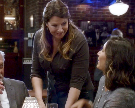 11 Angela Rizzoli played by Lorraine Bracco smiling while looking down at co-star.