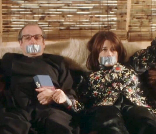 3 Lorraine Bracco and David Paymer laying in bed with duct tape over their mouths in Crazy for Love.