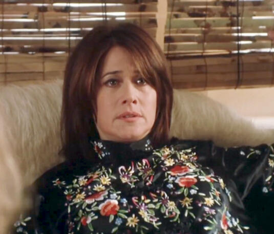 11 Lorraine Bracco laying in bed looking serious in a floral embroidered blouse in Crazy for Love.