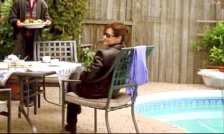 2 Lorraine Bracco wearing sunglasses while sitting outside by a pool in Custody of the Heart.