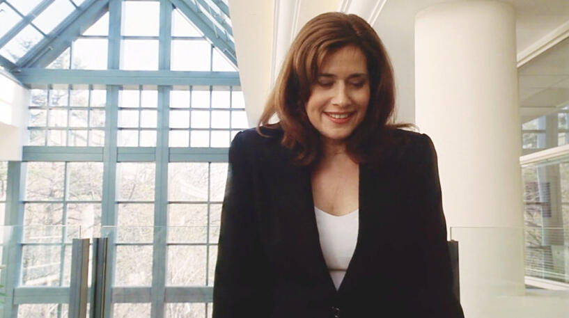 7 Lorraine Bracco smiling down in a black blazer in a scene from Custody of the Heart.