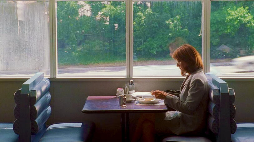 6 Dr. Jennifer Melfi sitting alone at a diner table eating breakfast in The Sopranos.