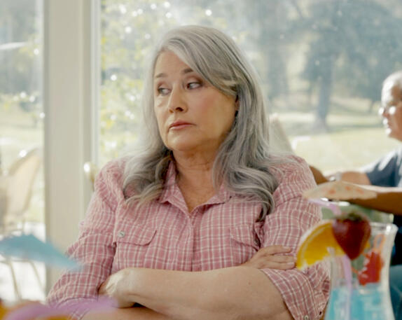 9 Lorraine Bracco sitting with arms crossed looking annoyed in The Mother, the Menacer, and Me