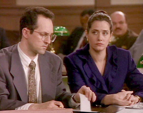 2 Lorraine Bracco in a dark blue suit sitting next to a man in a courtroom scene from Getting Gotti.