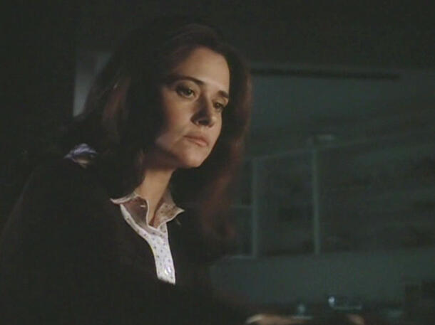 12 Lorraine Bracco looking down thoughtfully in a dimly lit indoor scene from the movie Getting Gotti.