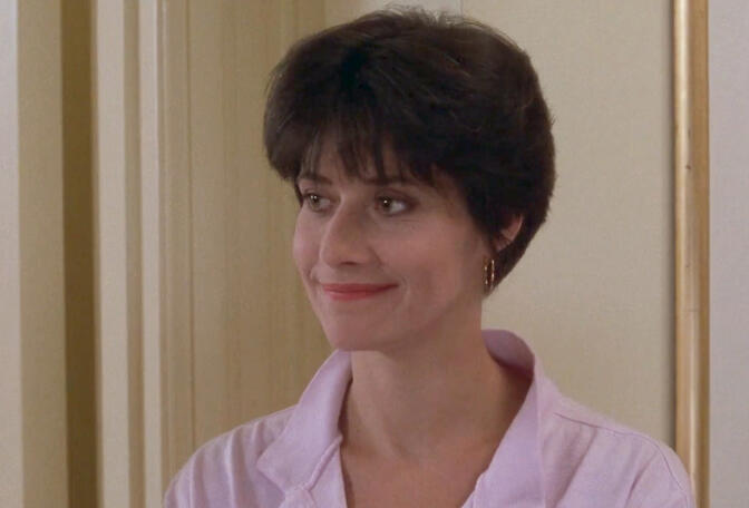 12 Lorraine Bracco smiling in a pink shirt, movie still from The Dream Team.
