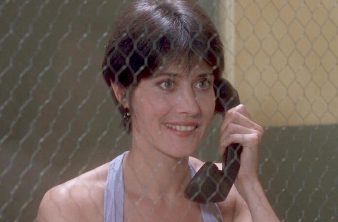 11 Lorraine Bracco smiling on the phone in a prison visitation room in The Dream Team.