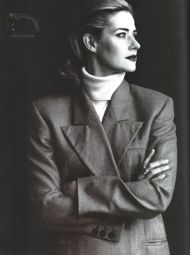 Mirabella magazine fashion spread featuring a black and white portrait of actress Lorraine Bracco. She is looking to the side with arms crossed, wearing a white turtleneck sweater and a structured plaid Gucci blazer.