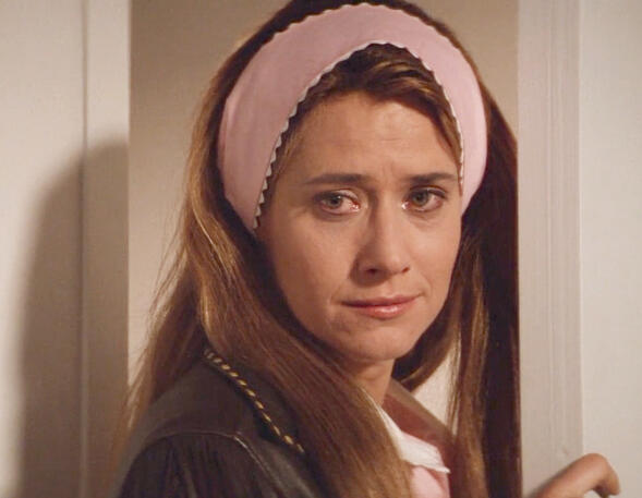 3 Lorraine Bracco wearing a pink headband while crying in a doorway in the film Radio Flyer.