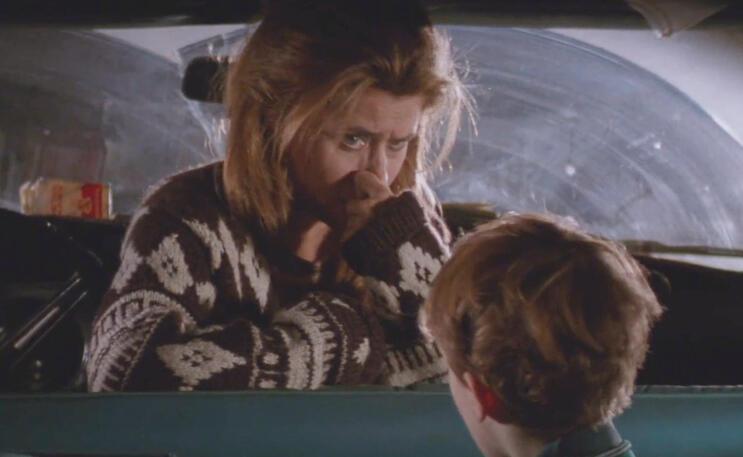 8 Lorraine Bracco wearing a patterned sweater looking intently at a young Joseph Mazzello while pinching her nose in Radio Flyer.