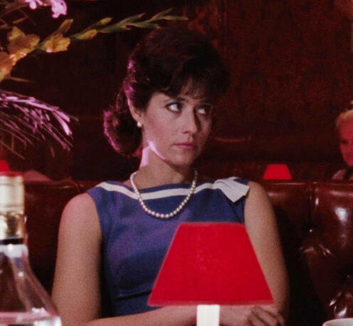 one of my favourite screenshots of her :) Lorraine Bracco wearing a pearl necklace sitting at a restaurant table in a scene from Goodfellas.
