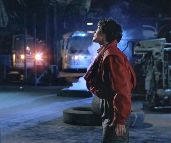 11 Lorraine Bracco standing outside at night in a red jacket in dancing scene from Sing 1989.