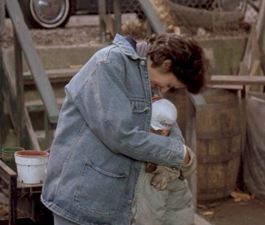 10 Lorraine Bracco wearing a denim jacket and hugging a child in Someone to Watch Over Me.